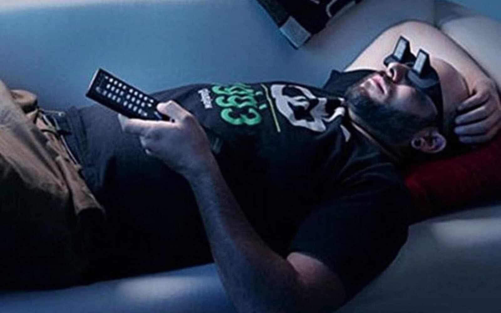 Man lying on a couch watching TV wearing prism glasses